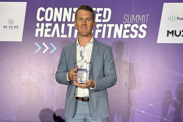 The founder accepting the Innovation Award trophy on stage.